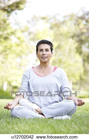 Stock Image - Senior Woman Doing Yoga In Park. Fotosearch
