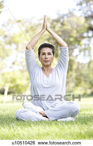 Stock Photograph - Senior Woman Doing Yoga In Park. Fotosearch