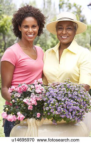 Stock Image - Senior Woman With Adult Daughter Gardening Together. Fotosearch