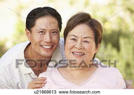 Stock Image - Senior Woman With Adult Son In Garden. Fotosearch