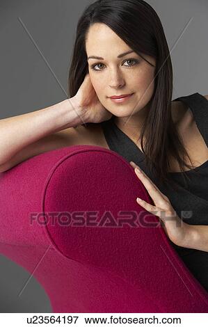 Stock Photo - Studio Portrait Of Woman Relaxing On Pink Chaise Longue. Fotosearch
