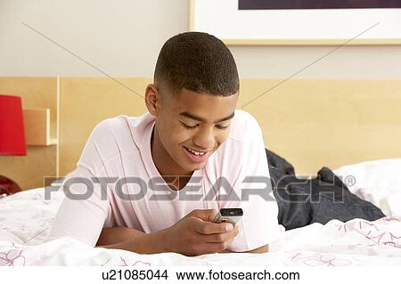 Picture - Teenage Boy In Bedroom With Mobile Phone. Fotosearch