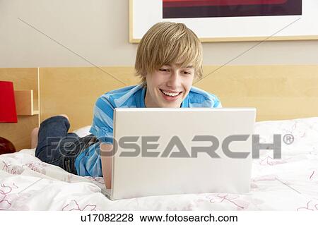 Stock Photo - Teenage Boy Using Laptop In Bedroom. Fotosearch