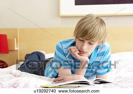 Stock Image - Teenage Boy Writing In Diary In Bedroom. Fotosearch