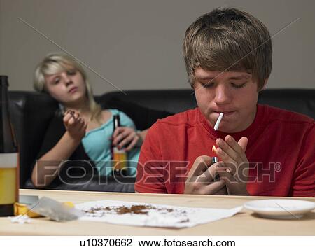 Stock Image - Teenage Couple Taking Drugs At Home. Fotosearch