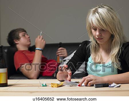 Stock Image - Teenage Couple Taking Drugs At Home. Fotosearch