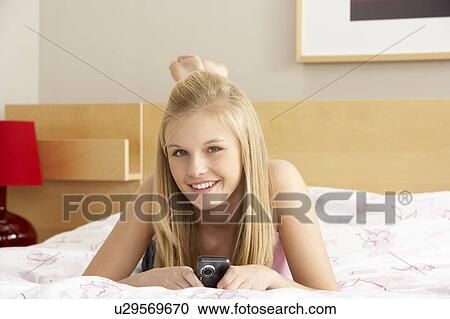 Stock Image - Teenage Girl In Bedroom With Mobile Phone. Fotosearch