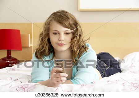 Stock Photo - Teenage Girl In Bedroom With Mobile Phone. Fotosearch