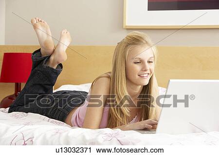 Stock Image - Teenage Girl Using Laptop In Bedroom. Fotosearch