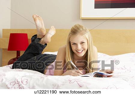 Stock Image - Teenage Girl Writing In Diary In Bedroom. Fotosearch
