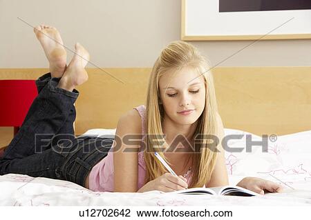 Stock Image - Teenage Girl Writing In Diary In Bedroom. Fotosearch