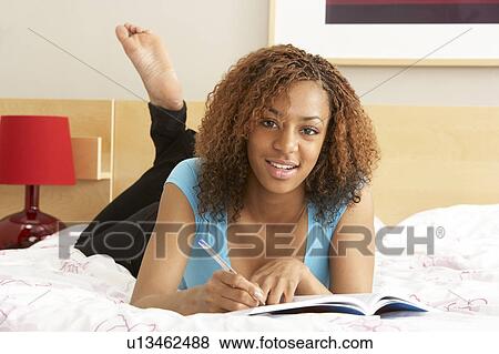 Stock Photo - Teenage Girl Writing In Diary In Bedroom. Fotosearch