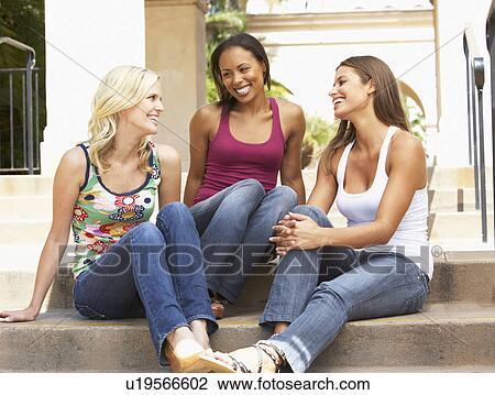 Stock Image - Three Girlfriends Sitting On Steps Of Building. Fotosearch