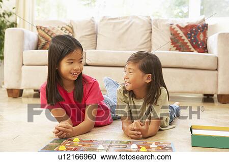 Stock Image - Two Girls Playing Board Game At Home. Fotosearch
