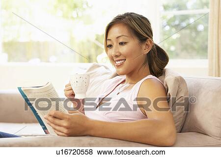 Stock Photo - Woman Reading Book With Drink At Home. Fotosearch