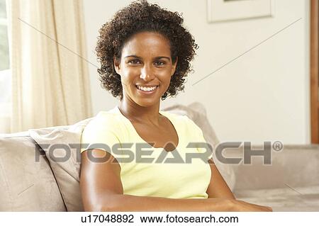 Stock Image - Woman Relaxing On Sofa At Home. Fotosearch
