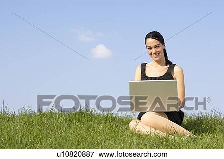 Stock Photo - Woman Using Laptop Outdoors In Summer Countryside. Fotosearch