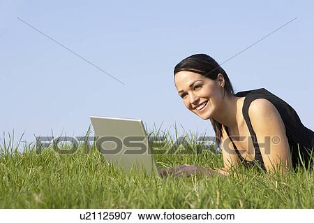Stock Photo - Woman Using Laptop Outdoors In Summer Countryside. Fotosearch