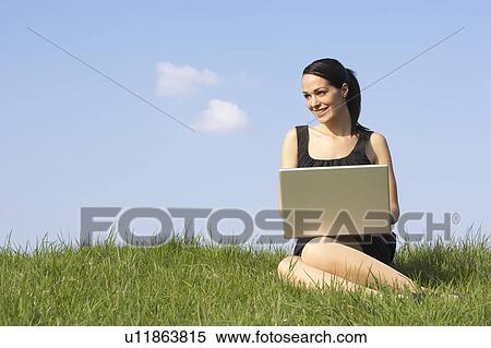 Stock Photography - Woman Using Laptop Outdoors In Summer Countryside. Fotosearch