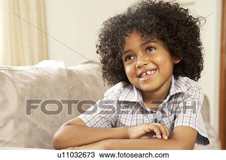 Stock Image - Young Boy Relaxing On Sofa At Home. Fotosearch