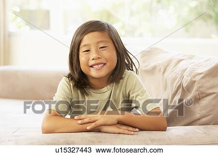 Stock Image - Young Boy Relaxing On Sofa At Home. Fotosearch