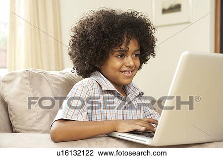 Stock Image - Young Boy Using Laptop At Home. Fotosearch