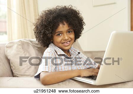 Stock Photo - Young Boy Using Laptop At Home. Fotosearch