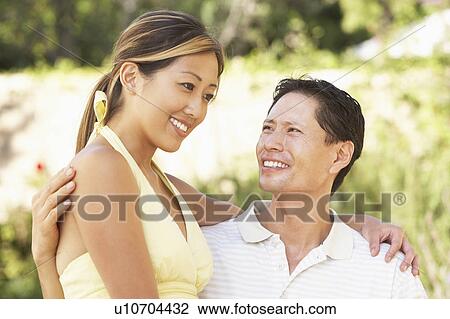 Stock Image - Young Couple Hugging In Garden. Fotosearch