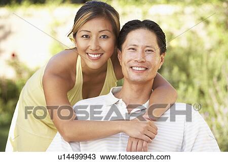 Stock Image - Young Couple Hugging In Garden. Fotosearch