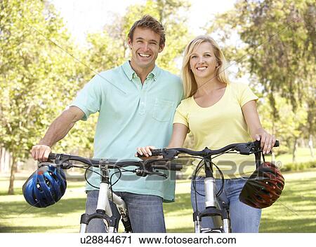 Stock Image - Young Couple On Cycle Ride in Park. Fotosearch