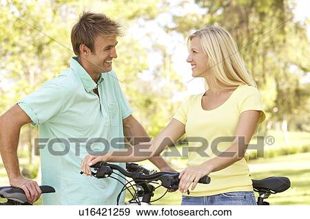Stock Photo - Young Couple On Cycle Ride in Park. Fotosearch