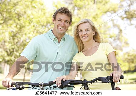 Stock Photo - Young Couple On Cycle Ride in Park. Fotosearch
