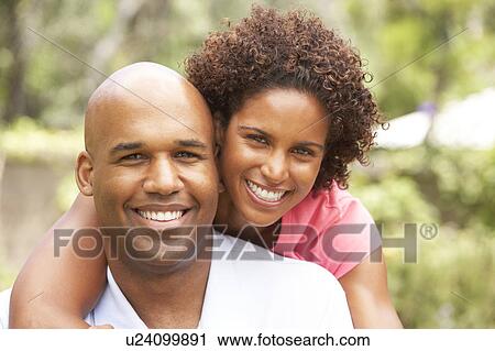 Stock Image - Young Couple Relaxing In Garden. Fotosearch