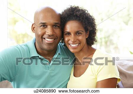 Stock Image - Young Couple Relaxing On Sofa At Home. Fotosearch