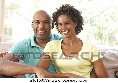Stock Photo - Young Couple Relaxing On Sofa At Home. Fotosearch