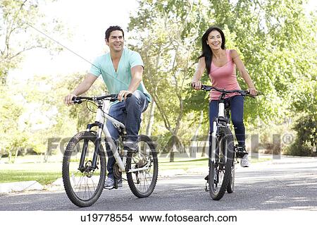 Young Couple Riding Bike In Park View Large Photo Image Picture - Young Couple Riding Bike In Park. Fotosearch