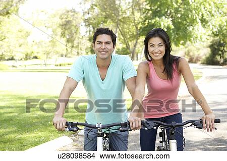 Young Couple Riding Bikes In Park View Large Photo Image Picture - Young Couple Riding Bikes In Park. Fotosearch