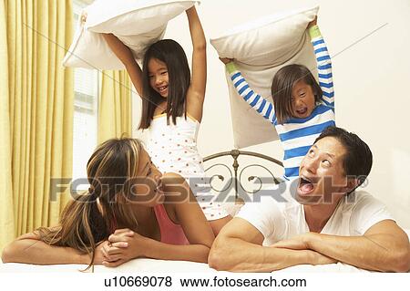 Stock Photo - Young Family Having Pillow Fight In Bedroom. Fotosearch