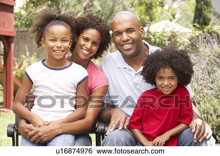 Stock Photograph - Young Family Relaxing In Garden Together. Fotosearch