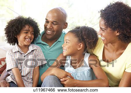 Stock Photograph - Young Family Relaxing On Sofa At Home. Fotosearch
