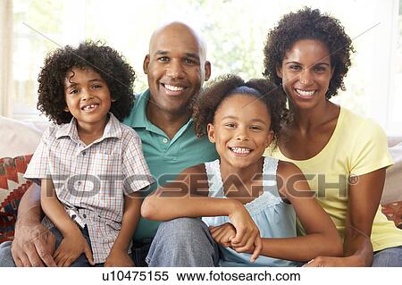 Stock Photography - Young Family Relaxing On Sofa At Home. Fotosearch