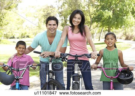 Stock Photo - Young Family Riding Bikes In Park. Fotosearch
