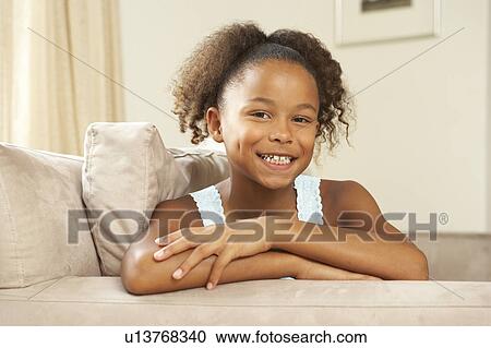 Stock Image - Young Girl Relaxing On Sofa At Home. Fotosearch