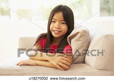 Stock Image - Young Girl Relaxing On Sofa At Home. Fotosearch