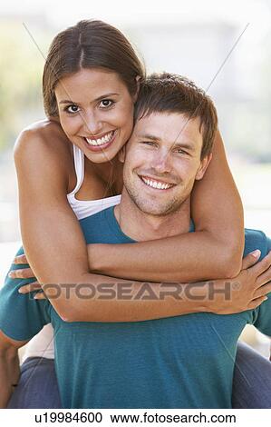Stock Image - Young Man Giving Woman Piggyback Outdoors. Fotosearch