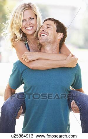Stock Image - Young Man Giving Woman Piggyback Outdoors. Fotosearch