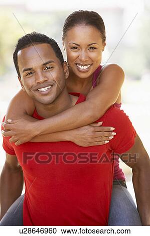 Stock Image - Young Man Giving Woman Piggyback Outdoors. Fotosearch
