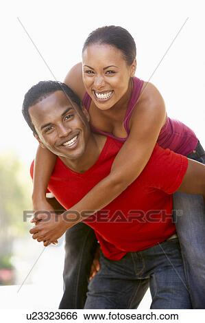 Stock Photograph - Young Man Giving Woman Piggyback Outdoors. Fotosearch