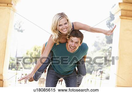 Stock Photography - Young Man Giving Woman Piggyback Outdoors. Fotosearch