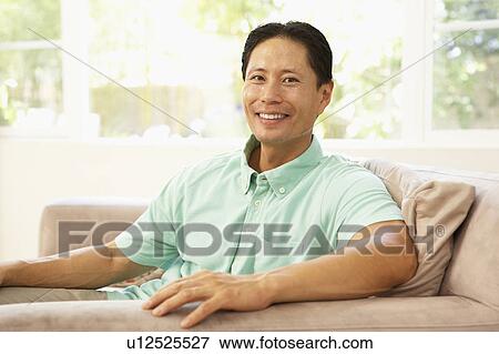 Stock Photo - Young Man Relaxing On Sofa At Home. Fotosearch